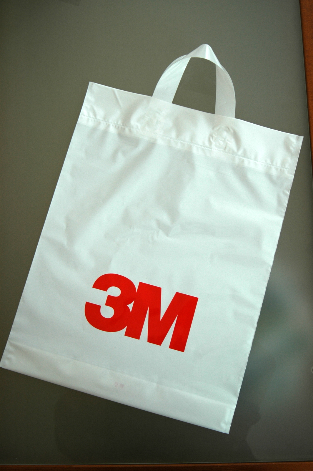 Plastové tašky z PE fólii s páskovými ušami s logom spoločnosti 3M, pre ktorú sme potláčali aj trička